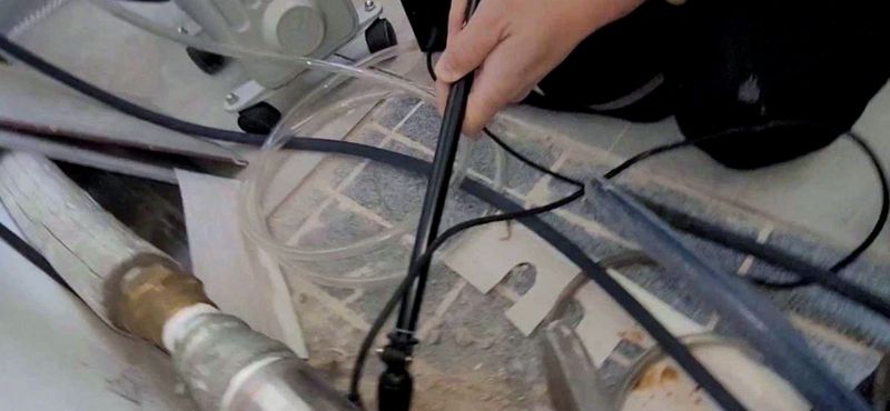 보일러 옆 배관 사이로 청음기를 대고 새는 소리를 듣는 모습
