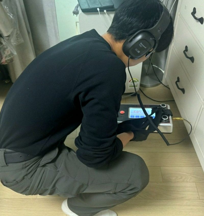 바닥에 청음 장비를 대고 누수 소리를 듣는 모습