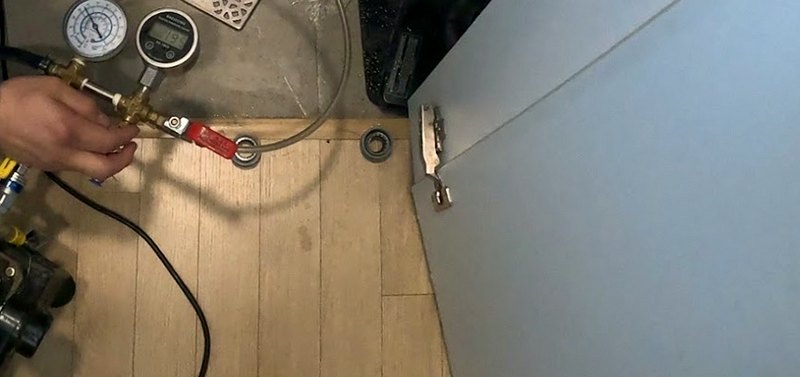화장실 배수구 옆에서 배관에 압력계를 물리고 밸브를 조작하는 손