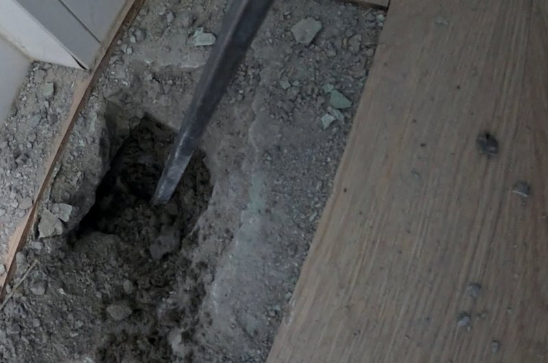 표시한 벽 하단 모서리 바닥을 정으로 조금씩 깨어 들어가는 모습