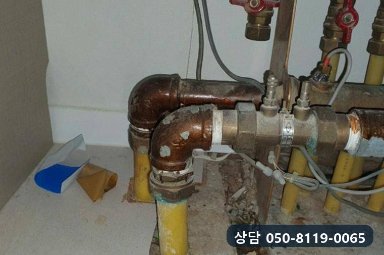 바닥으로 내려가는 노란 난방관과 연결된 난방 분배기