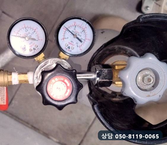 탐지용 가스 용기에 압력 조절기와 게이지 두 개를 연결한 모습