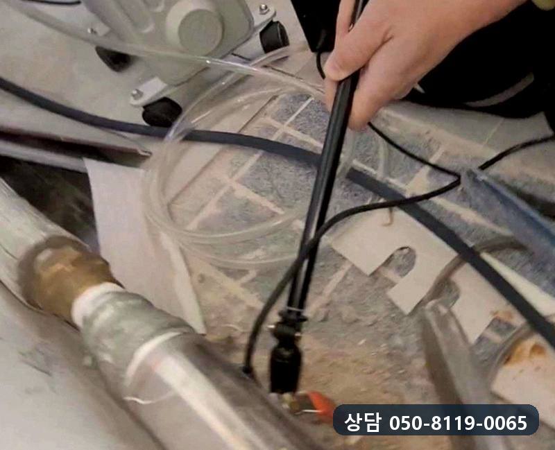 배관이 지나는 바닥 위에 탐지기 끝을 대고 반응을 살피는 모습
