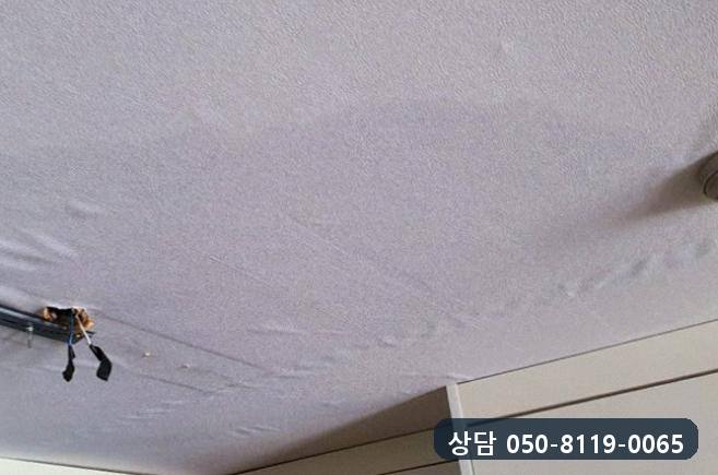 주방 천장 등기구를 떼어 낸 자리에 전선이 늘어지고 도배지가 물결처럼 눌린 모습