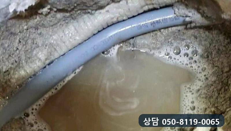 바닥 속 회색 온수관 둘레에 고인 물과 가장자리에 맺힌 비눗물 거품