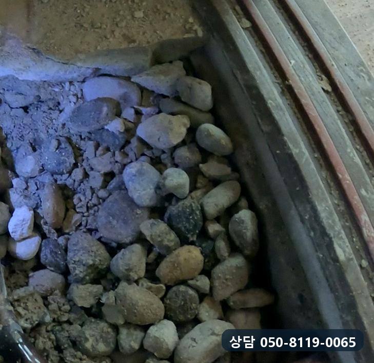 문틀 옆 바닥을 걷어 내자 드러난 자갈층과 그 아래 배관