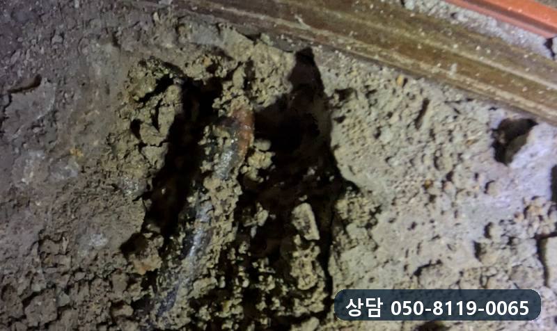 문틀 앞 시멘트층을 걷어 내자 젖은 자리 속에 드러난 녹슨 배관