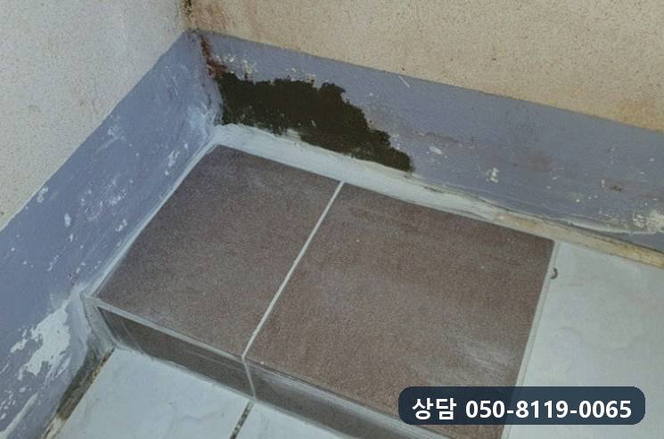 걸레받이 위 벽 모서리가 물을 먹어 검게 얼룩진 모습