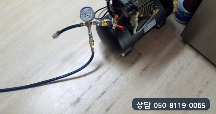 주방 바닥에 공기압 장비를 놓고 호스와 압력계를 연결한 모습