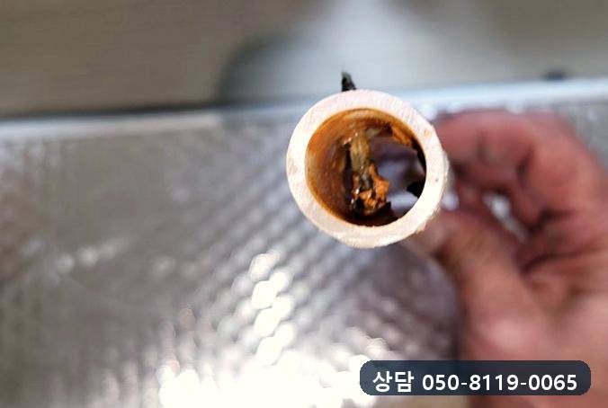 잘라 낸 온수관 안쪽에 갈색 찌꺼기가 끼어 있는 모습