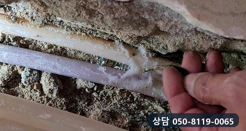 바닥 속에서 드러난 온수관의 갈라진 자리를 손으로 가리키는 모습