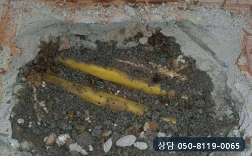 문틀 앞 마루와 미장층을 걷어 내자 드러난 노란색 온수관 두 줄